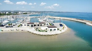 A marina with boats, a white building with a roof, and a beach area.