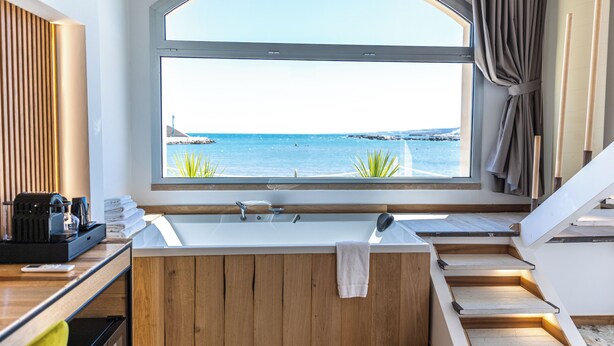 A modern bathroom with a large window, a bathtub, a sink, and a wooden vanity.