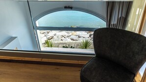A room with a curved glass window overlooking a rocky landscape and a body of water.