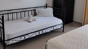 Ein Schlafzimmer mit einem Einzelbett, einem Kleiderschrank und einem Fenster mit Vorhängen.