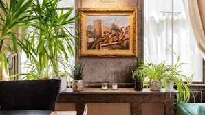 A room with a large window, a painting on the wall, and several potted plants on the windowsill. - Chic Marylebone Central Flat (London)