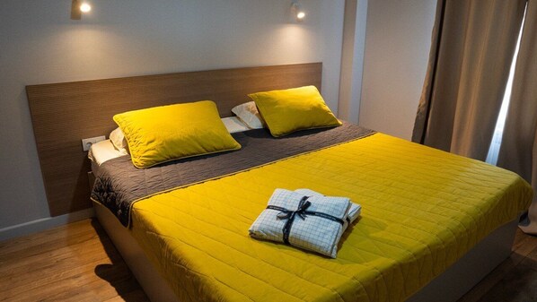 Una cama con cabecera de madera, dos almohadas y una colcha amarilla.