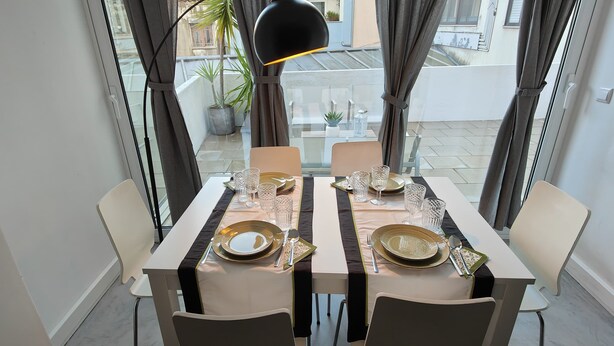 A dining table set for two with a modern design, positioned near a window with curtains.