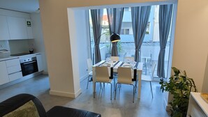 A modern kitchen with white cabinets, a built-in oven, and a dining area with a table and chairs.
