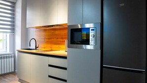 Una cocina moderna con microondas integrado, electrodomésticos de acero inoxidable y un salpicadero de madera.
