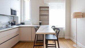 A modern kitchen with a marble countertop, black chairs, and a white dining table.