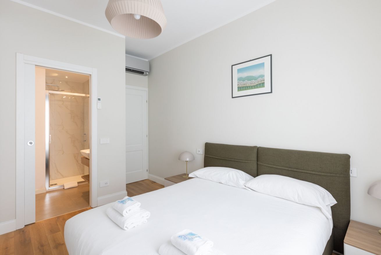 Une chambre d’hôtel avec un lit, une douche, un tableau encadré au mur et une lampe sur la table de chevet.
