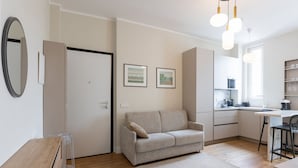 A modern apartment with a kitchenette, a sofa, a dining area, and a wooden floor.