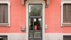 A building facade with a large glass door, a visible number '133' above the door, and a small mailbox on the wall.