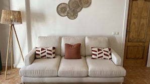 A three-seater sofa with patterned cushions, a floor lamp, and decorative wall art.
