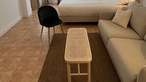 A hotel room with a bed, a sofa, a chair, a small table, and a ceiling fan.