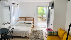 A bedroom with a bed, a sofa, a table, and a TV. - Peaceful Studio by the Beach in Bodrum (Muğla)
