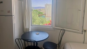 A small room with a window, a table, two chairs, and a bed. - Peaceful Studio by the Beach in Bodrum (Muğla)