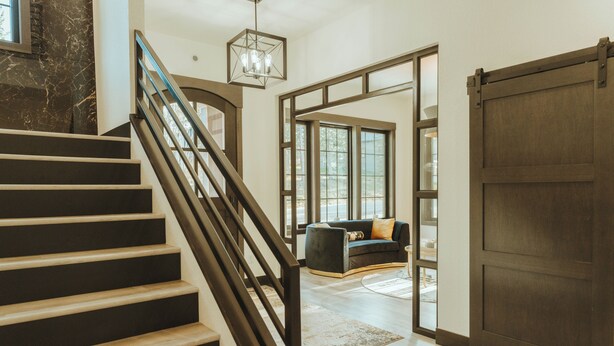 A staircase leading to a living area with a large sliding door, a sofa, and a chandelier.