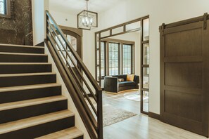 Un escalier menant à un espace de vie comprenant une grande porte coulissante, un canapé et un lustre.