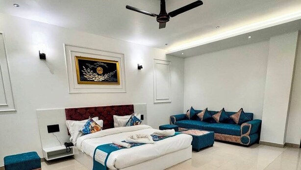 A modern bedroom with a bed, a sofa, and a ceiling fan. - HOTEL PARAS CHITTORGARH (Chittorgarh)