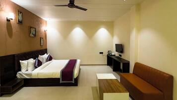 A hotel room with a bed, a sofa, a TV, and a ceiling fan.