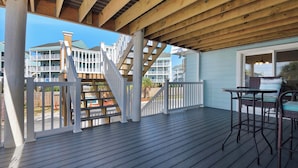 A wooden deck with a railing, a table, and chairs. - 🌊 Boardwalk F1 | Steps to Gulf, Bayfront Views, Walk to Peg Leg Pete’s 🌊 (Pensacola Beach)