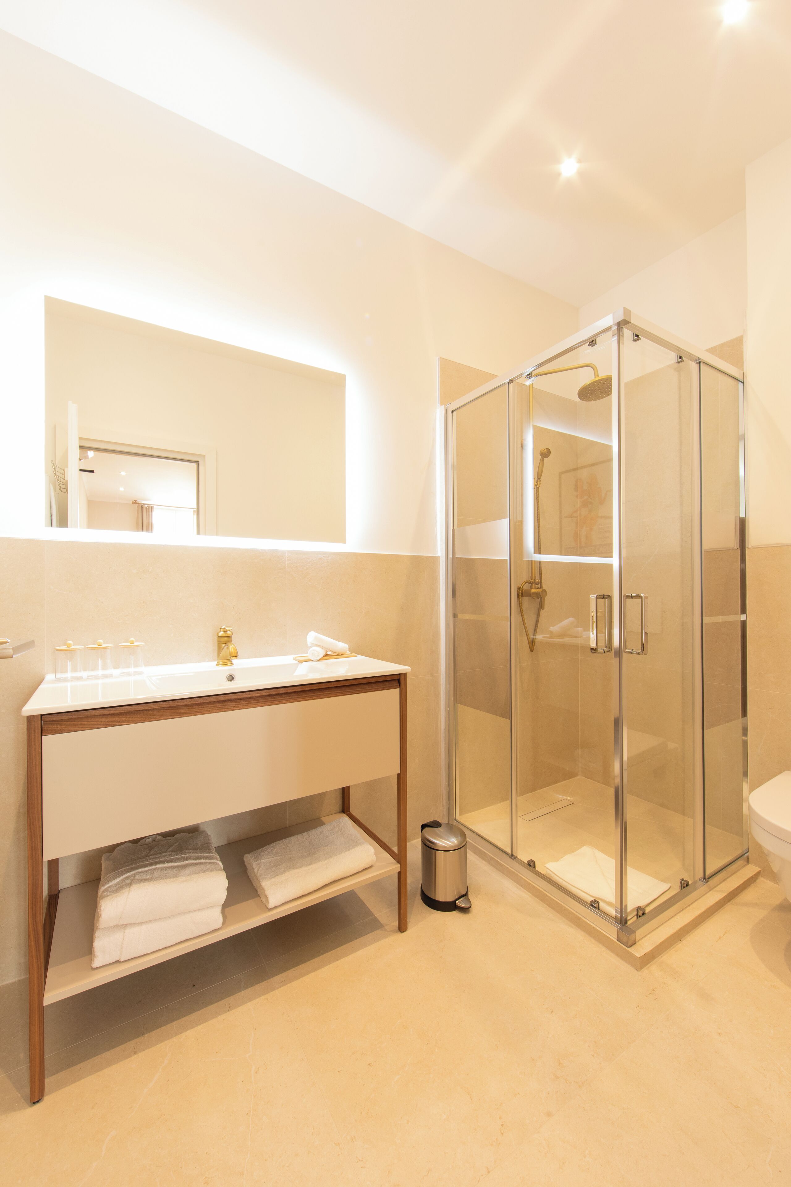 Et moderne badeværelse med bruseniche, vaskebord med spejl og toilet.