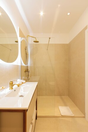 Uma casa de banho moderna com cabine de duche em vidro, lavatório branco e espelho grande.