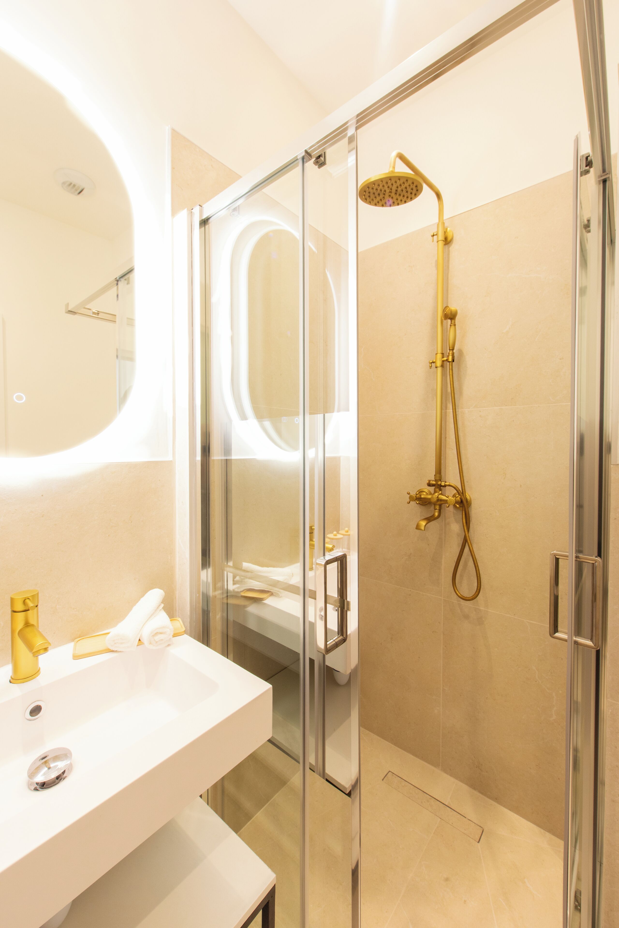 A modern bathroom with a glass-enclosed shower, a white sink, and a large mirror.