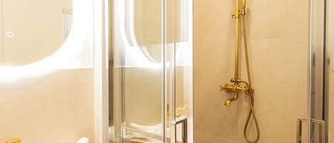 A modern bathroom with a glass-enclosed shower, a white sink, and a large mirror.