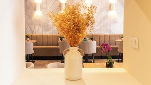 A white vase with dried flowers on a table in a modern interior with a sofa and chairs in the background. - Hotel Villa Botanica (Cannes)