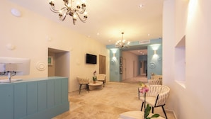 A spacious lobby with a reception desk, seating area, and a chandelier. - Hotel Villa Botanica (Cannes)