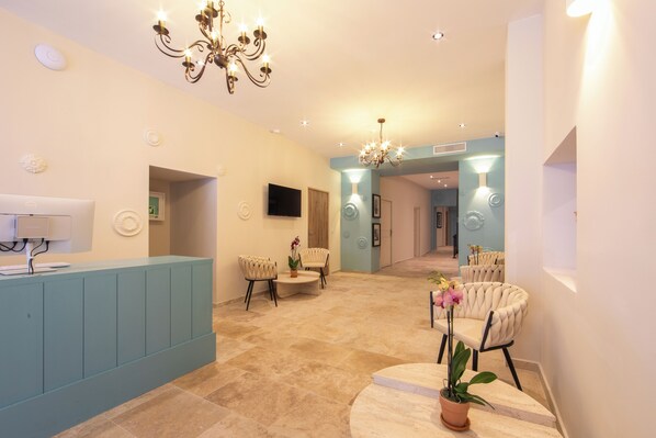 A spacious lobby with a reception desk, seating area, and a chandelier.