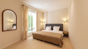 A bedroom with a large bed, a mirror, and two bedside lamps. - Hotel Villa Botanica (Cannes)