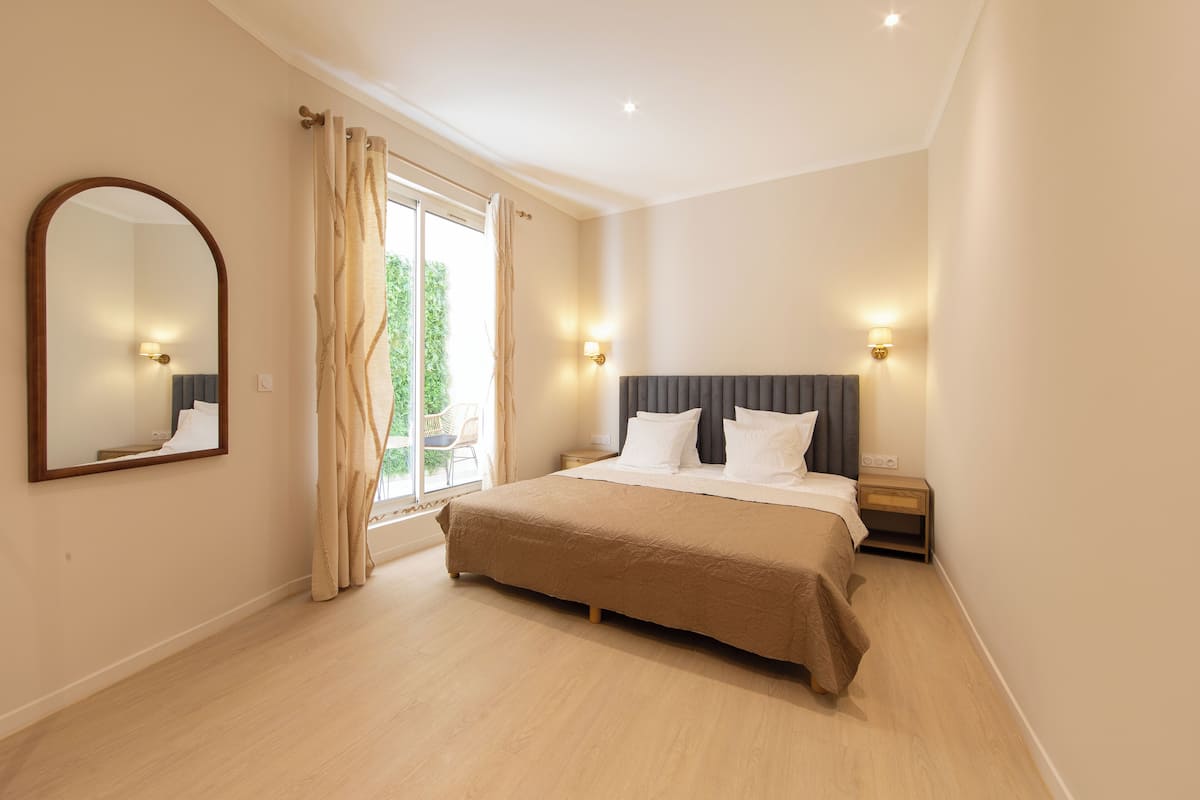A bedroom with a large bed, a mirror, and two bedside lamps.