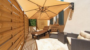 A patio with wicker furniture, a wooden fence, and a large canopy. - Hotel Villa Botanica (Cannes)