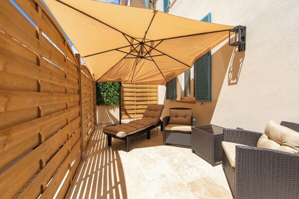 A patio with wicker furniture, a wooden fence, and a large canopy. - Hotel Villa Botanica (Cannes)