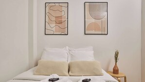 A neatly made bed with white linens, two pillows, and folded towels. There is a small wooden side table with a vase of flowers. - Magnificent Flat in Saint Germain des Pres (Paris)