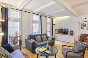 A modern living room with a sofa, a coffee table, a TV, and a bookshelf. - Magnificent Flat in Saint Germain des Pres (Paris)