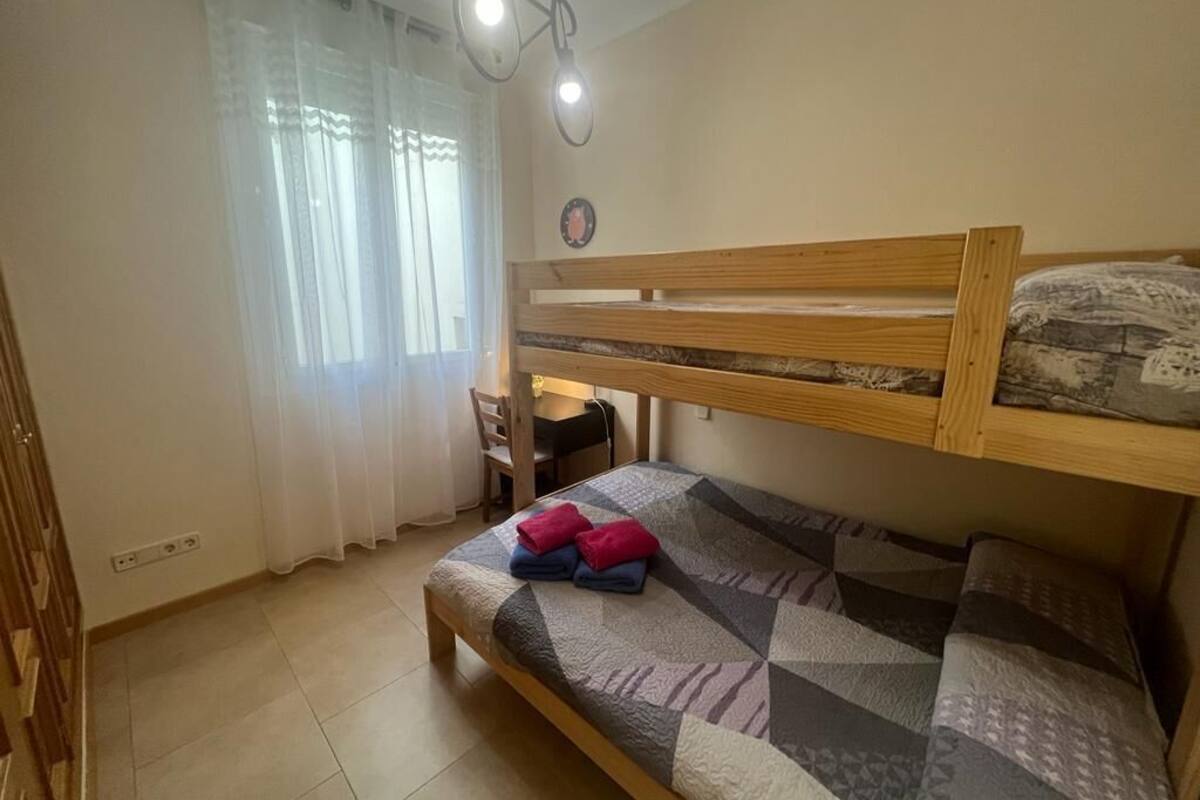 A bedroom with a bunk bed, a desk, and a chair.