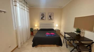 A bedroom with a bed, bedside tables with lamps, a desk, and two wall-mounted artworks.