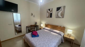 A bedroom with a bed, bedside tables, a mirror, and abstract wall art.