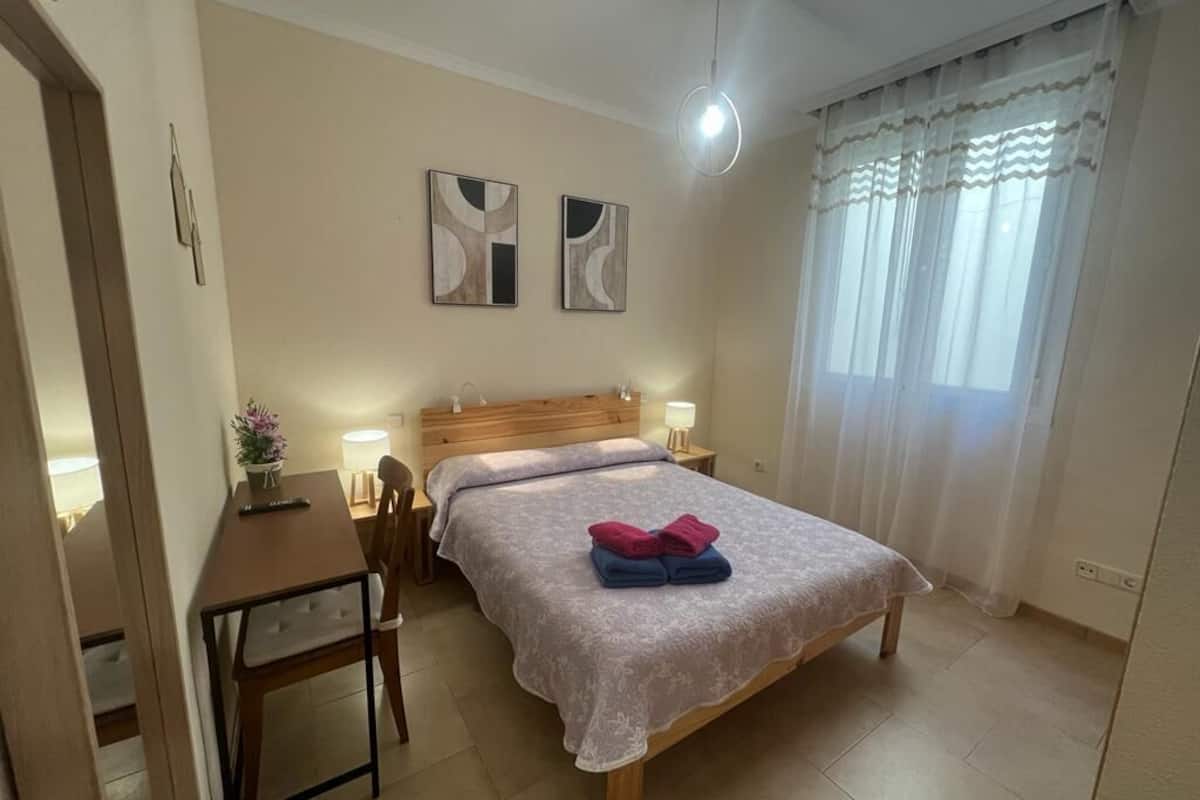 A bedroom with a bed, bedside tables, a desk, and a chair.