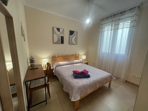 Ein Schlafzimmer mit einem Bett, Nachttischen, einem Schreibtisch und einem Sessel.