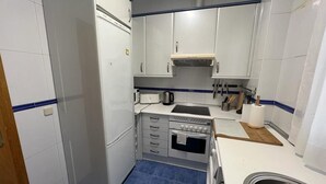 Una cocina pequeña con armarios blancos, un lavamanos y una estufa.