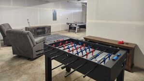 Une pièce équipée d’un baby-foot, d’un canapé, d’une petite télévision et d’une table de ping-pong.