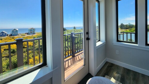 Une pièce dotée de grandes fenêtres donnant sur un paysage magnifique, avec une plage et des maisons en vue.