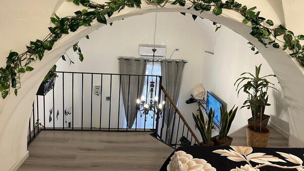 Une pièce spacieuse avec un plancher en bois, une table noire ornée de motifs floraux blancs et une plante en pot.