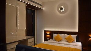 A modern hotel room with a large bed, bedside tables, and a built-in wardrobe. - SRS Suite (Bengaluru)
