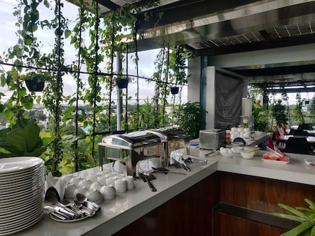 A restaurant kitchen with hanging plants, a buffet setup, and a city view.
