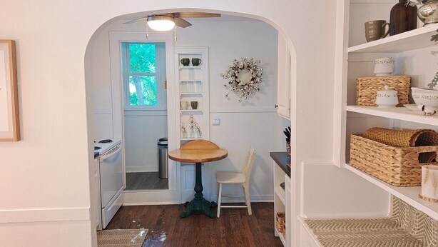 A kitchen with a wooden table, a chair, and a window with a view of greenery. - Charming 2-bedroom cottage with WiFi, AC in enjoyable Fort Madison (Fort Madison)
