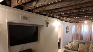 A living room with a large flat-screen TV, a sofa, a coffee table, and a fireplace. - Charming 2-bedroom cottage with WiFi, AC in enjoyable Fort Madison (Fort Madison)