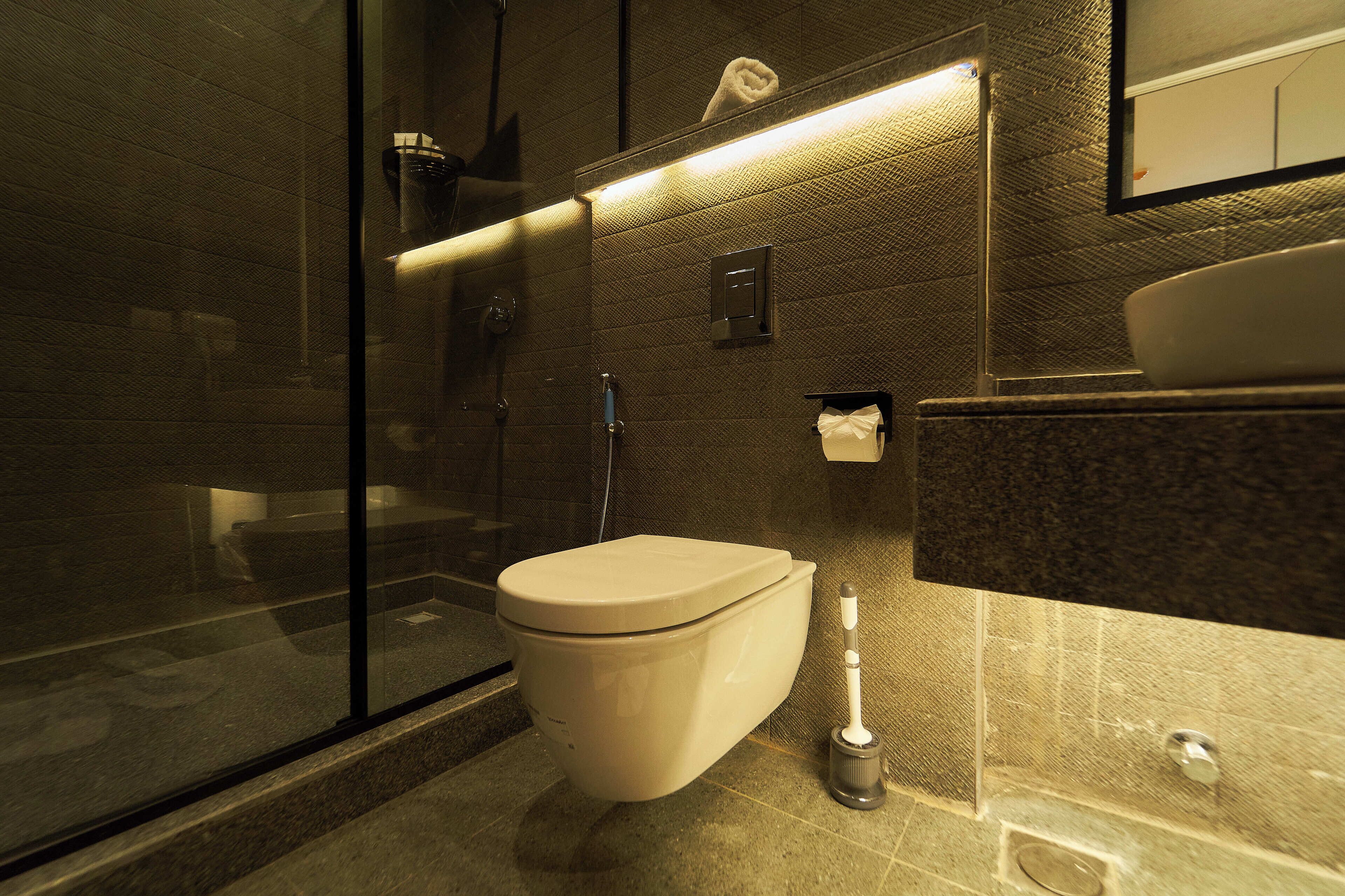 A modern bathroom with a toilet, bidet, and a glass shower enclosure.