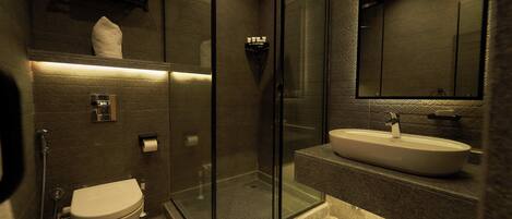 A modern bathroom with a glass-enclosed shower, a white sink, and a toilet.